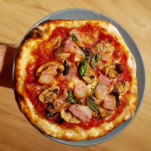 Pizza fatta in casa con pancetta, funghi e basilico